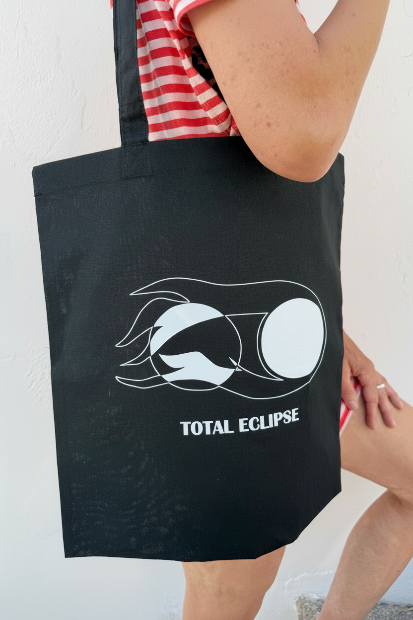 "Heliophagos Tote Bag — limited edition cotton tote by LKG Fashion. Inspired by the Total Eclipse 2026. Edition of 34, no re-runs. 38 × 42 cm."